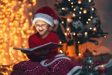 surprised child opening magic christmas book. xmas holiday concept