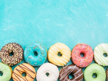 top view of assorted donuts on blue concrete background with copy space. colorful donuts background. various glazed doughnuts with sprinkles.
