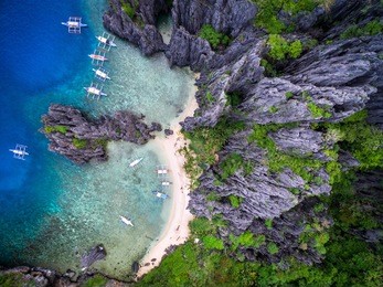 el nido, palawan, philippines, aerial view of boats and limestone cliffs at secret lagoon beach.