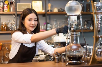attractive young beautiful caucasian barista make iced slow drip coffe working order concept and smiling look at camera.