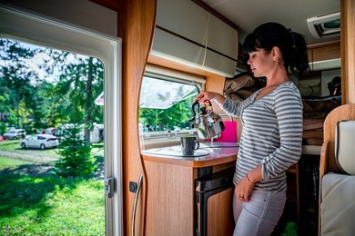 woman cooking in camper, motorhome interior. family vacation travel, holiday trip in motorhome rv, caravan car vacation.