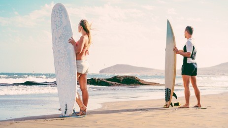 surfers couple waiting for the high waves on beach - sporty people with surf boards on the beach - extreme sport and vacation concept - soft ocus on female head - vintage filter