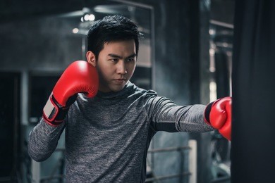young handsome man exercising with  boxing on punching bag in a gym