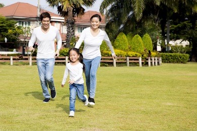 happy asian family running in the park. daughter mother and father.