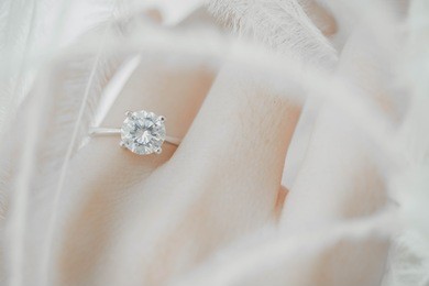 close up of elegant diamond ring on the finger with feather, love and wedding concept. (soft and selective focus.)