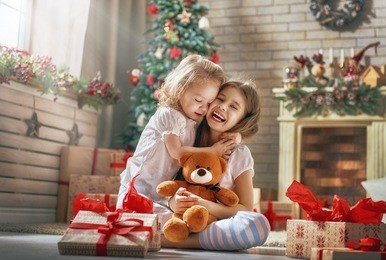 merry christmas and happy holidays! cheerful cute childrens girls opening gifts. kids wearing pajamas having fun near tree in the morning. loving family with presents in room.