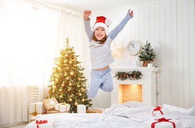 happy funny child girl  jumping in bed on christmas morning