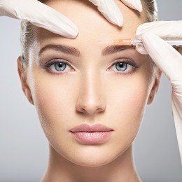 portrait of young caucasian woman getting botox cosmetic injection in forehead. beautiful woman gets botox injection in her face.