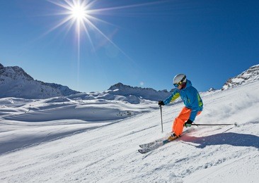 skier skiing downhill during sunny day in high mountains