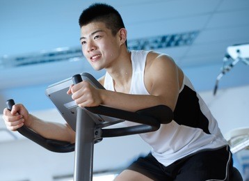 asian man cycling on exercise bike in gym