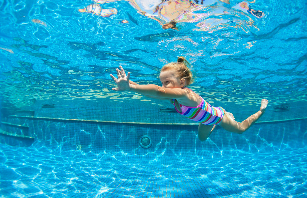 funny portrait of child learn swimming, diving in blue pool with fun - jumping deep down underwater with splashes. healthy family lifestyle, kids water sports activity, swimming lesson with parents.