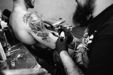 the process of creating a tattoo on the back of a man. professional tattoo.