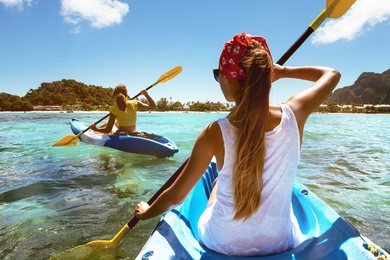 two girls at sea kayaks or canoe at tropical beach. travel or kayaking concept