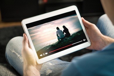 online movie stream with mobile device. man watching film on tablet with imaginary video player service.