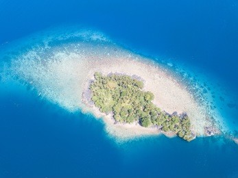 a tiny, idyllic island is surrounded by a fringing coral reef in the banda sea, indonesia. this remote region is home to thousands of beautiful islands and extraordinary underwater scenery.