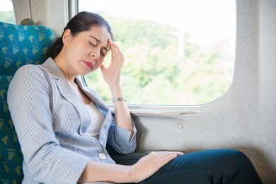 charming asian office woman feel headache painful on her business train travel journey sitting on her seat.