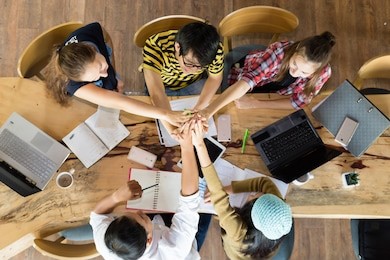 group of young students in cooperation with their academic assignment. top view shot of young people studying together around a table. students together at school table working homework and have fun.
