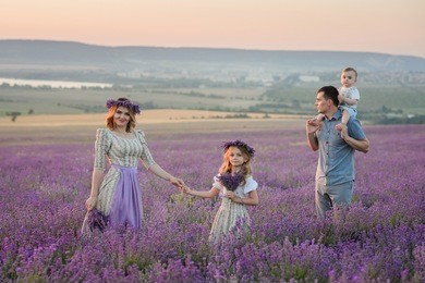 happy family in a field of lavender on sunset. girls in amazing dresses walk on the lavender field.