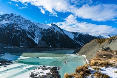 winter mountain landscape with snow and frozen lake on sunny day. mount cook national park, new zealand. nature background