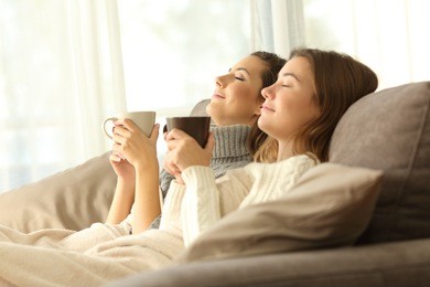 two relaxed roommates in winter sitting on a sofa in the living room of a house interior