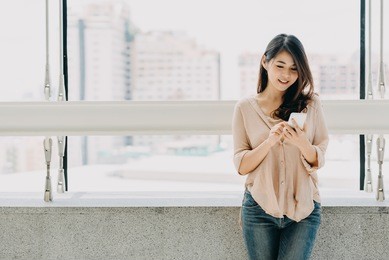 beautiful asian woman using smartphone in modern office building