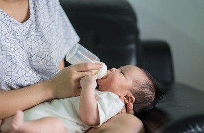 baby girl sleeping on mother's laps and drinking milk from bottle at home., background., concept of love.
