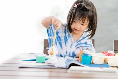 portrait of adorable little asian girl holding a paintbrush and working on a painting for art class in school.confidence positivity freedom be creative concept.