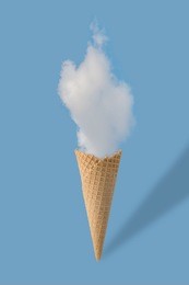 ice cream cone and white cloud on pastel blue background. flat lay. minimal summer concept.