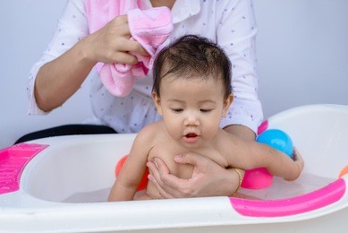 asian newborn baby is taking bath,baby taking a bath