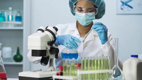 young medic taking blue liquid sample and doing biochemical research, laboratory