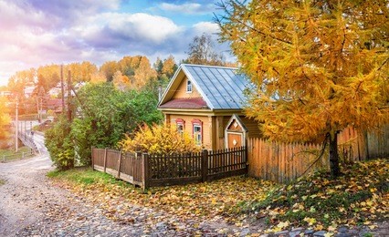 yellow wooden russian house and autumnal larch on the street descent of the mount of freedom in the autumn plyos