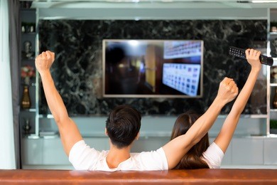 young asian couple in exciting moment, relax and   watching television in living room.