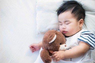 newborn baby sleep with teddy bear on ther bed