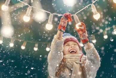 happy child playing on a snowy winter walk. little girl enjoying the holidays. portrait kid on dark background.
