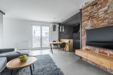 open plan studio with tv screen on exposed brick wall