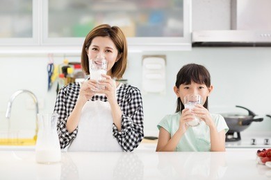 happy mother and child in kitchen drinking milk