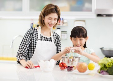 happy mother and child in kitchen preparing cookies

