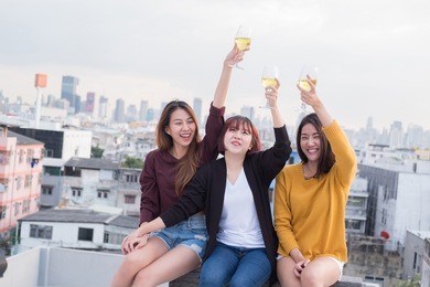 youth friendship party concept. group of asian friends drinking and having fun outdoor cheering at top roof.