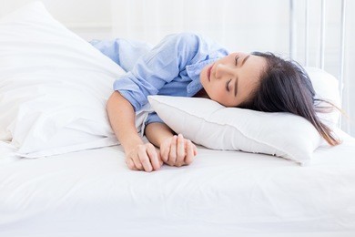 beautyful asian woman in blue shirt sleep on white bed with window light