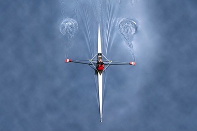 unique perspective of independent free spirit kayak adventurer rowing alone in peaceful serene calm waters with sky reflection