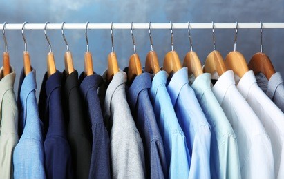 male jackets and shirts hanging on clothing rail indoors