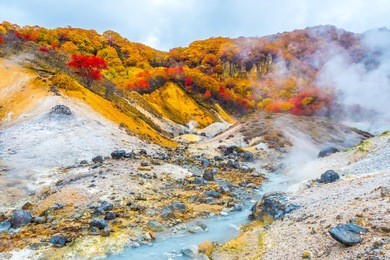 jigokudani hell valley in hokkaido, japan. hell valley in japanese is 'noboribetsu'. it is one of the famous tourist destination to visit. white heavy sulfur gas steaming from the ground smell bad.