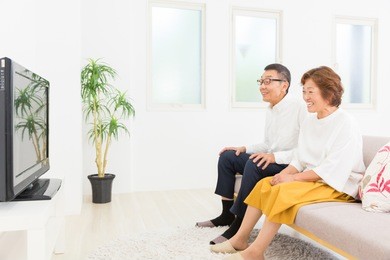 asian senior couple watching tv in living room