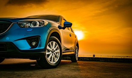 blue compact suv car with sport and modern design parked on concrete road by the sea at sunset. environmentally friendly technology. business success concept.