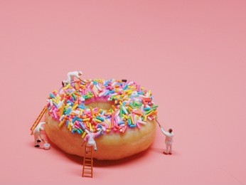 miniature people painting color on donut.
