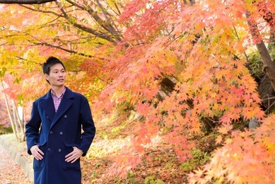 chinese man with maple leaves in autumn background