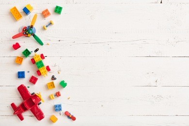 top view on multicolor toy bricks on white wooden background. children toys on the table.