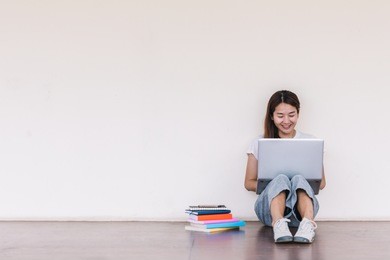 college student girl making report with laptop , sitting at school building. outdoor education concept.