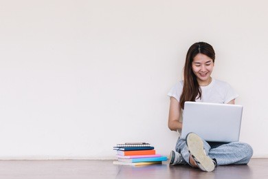college student girl making report with laptop , sitting at school building. outdoor education concept.