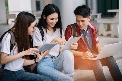 group of attractive young people using a laptop and tablet, sitting on the floor, top view. social media online concept.